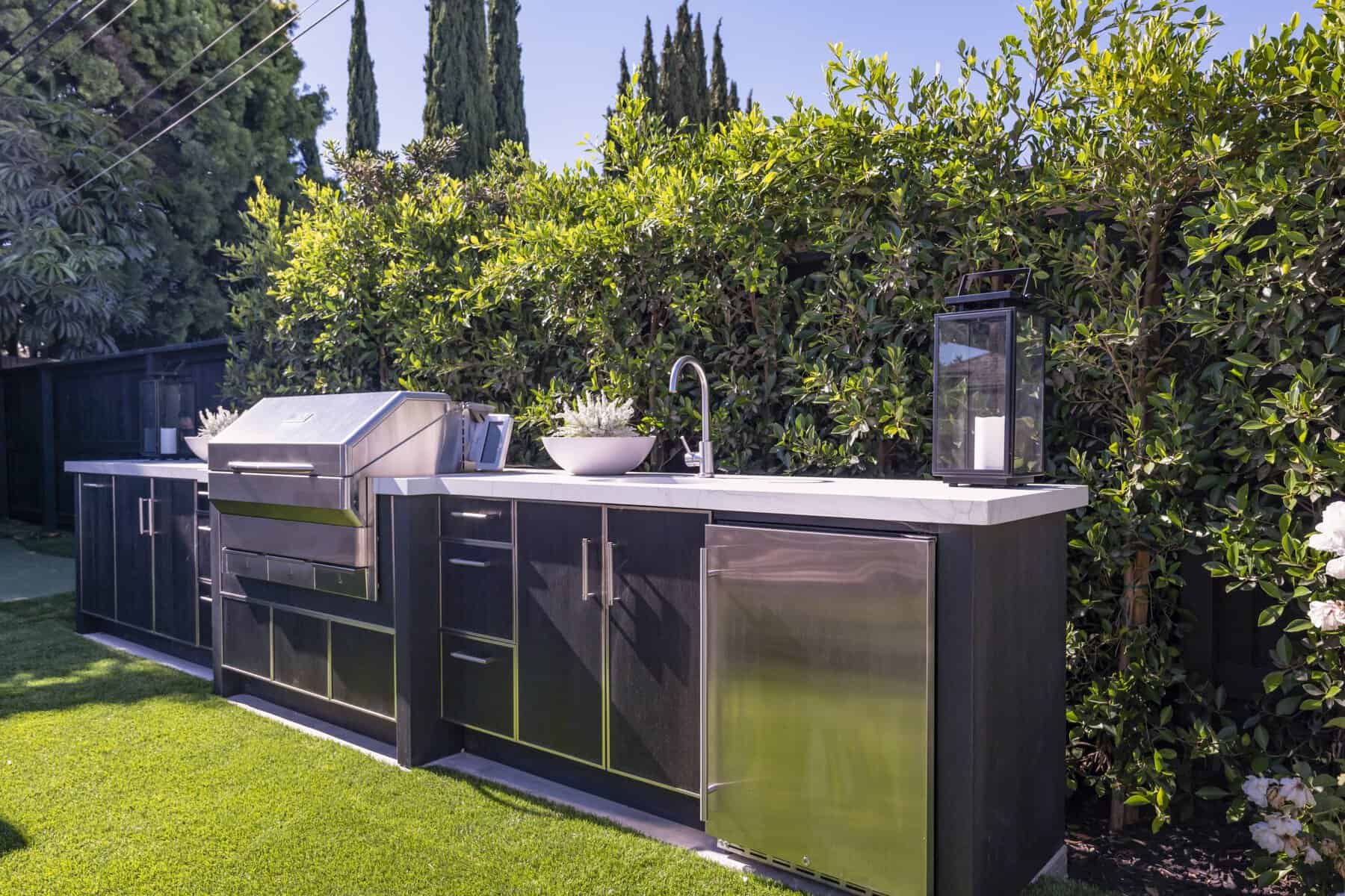 Modern outdoor kitchen with stainless steel grill, sink, and cabinets